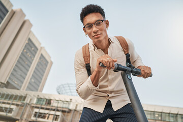 Scooter, city and portrait of a student man for travel and transportation with carbon footprint, eco friendly and urban lifestyle. Young gen z college or university person with an electric scooter © N F/peopleimages.com