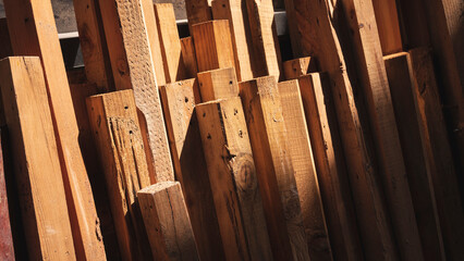 Light and shadow on surface of many old timber leaning against the wall in storage room, remaining...