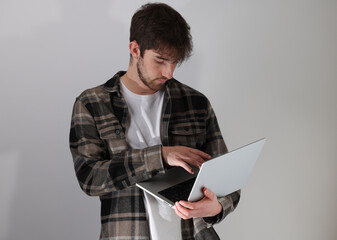 jeune homme debout utilisant un ordinateur portable. Sur fond gris