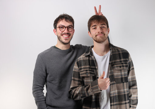 portrait de deux jeunes adultes de 20 ans. L'un d'eux fait une blague &agrave; son ami en lui faisant des oreilles de lapin avec sa main.