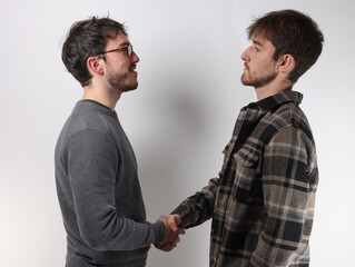 deux jeunes hommes se serrent la main pour se dire bonjour ou pour conclure un accord © Tof - Photographie