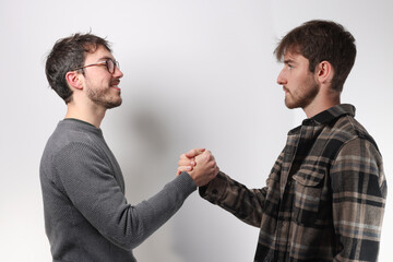 deux jeunes hommes se serrent la main pour se dire bonjour ou pour conclure un accord © Tof - Photographie