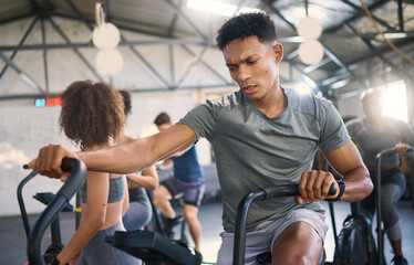 Gym, fitness and man on a spinning bike for exercise, health and cross training, power and motivation. energy, spinning bike and black man on air bike and sports center for wellness, workout and fit