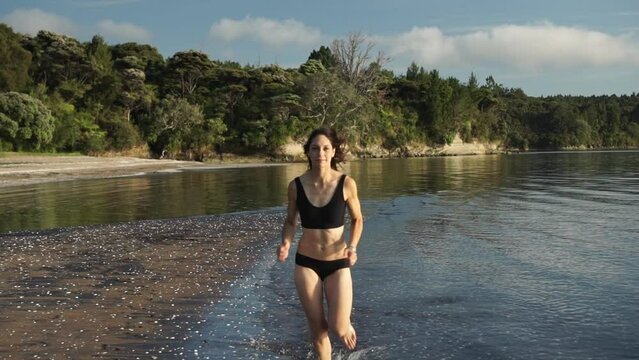 Girl running on beach, healthy lifestyle, front following gimbal view in slow motion