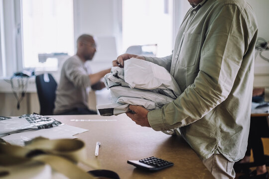 Midsection of male design professional holding packages at workshop