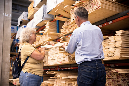 Male and female customers choosing plank at hardware store
