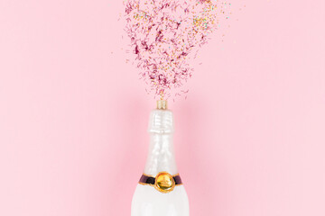 A Christmas tree bauble in the shape of a white champagne bottle. Golden and pink glitter come out...