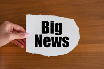 Big News - close up text on the slip. Woman hand holds a piece of paper with text. Information...