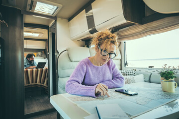 People man and woman in van life day inside camper van. Woman using phone gps map to plan next...