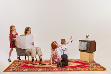 Portrait of young family watching TV isolated over grey background. Cheerful time together