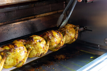 Chef of the kebab restaurant, with a metal tool controlling the chicken grill