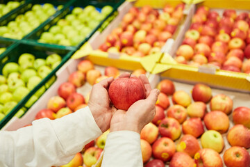 Hände eines Kunden halten einen Apfel auf dem Markt