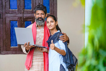 Obraz premium indian farmer daughter holding laptop and showing thumps up with father