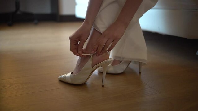Caucasian model in a hotel wearing a white party dress, cinematic shot putting on her high heels