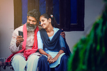 Indian farmer using smartphone with his daughter at home