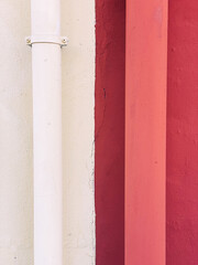 Separation of two houses. One white side, one red. Two drains in different colours
