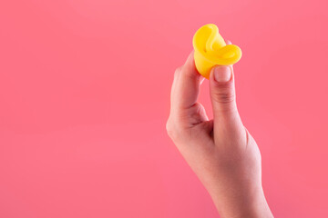 Close up view of woman holding yellow menstrual cup isolated over pink background, woman's period, menstrual cup in hands, modern methods for crytical days. Gynecology and hygiene products concept
