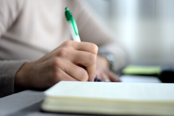 Fototapeta premium woman's hand writing in a diary using a ballpoint pen. selective focus