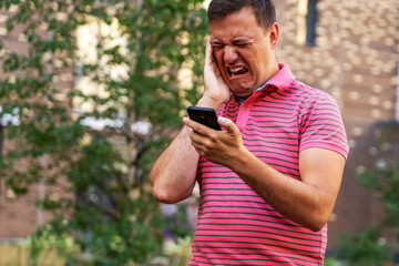 Millennial man using smartphone shocked by reading online news, frowning guy holding cell phone see warning notification. Confused guy looks at phone screen in surprise and stands outside at summer.