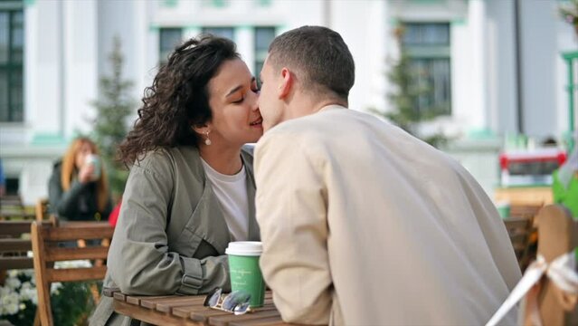 A romantic couple outdoors near a cafe. Kissing, coffee on the table. Autumn atmosphere. Slow motion