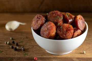 Obraz premium Slices of smoked pork sausages in a bowl on wood