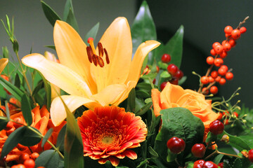 Flower bouquet with lily, rose and berries in warm yellow, orange and red autumn colours