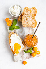 Sliced artisan homemade bread with ricotta or cottage cheese and orange jam on light background....