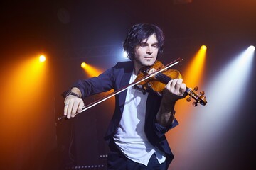 Violinist a player with a violin instrument in his hands. Artist of classical music or alternative music direction. Concept of stage art and performance.
