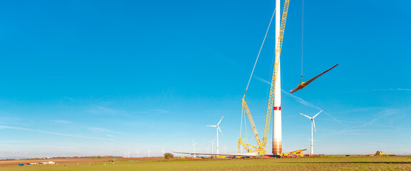 Construction work of wind turbine. crane is holding, grabing a blade of a wind turbine. Building...