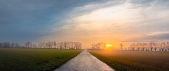 asphalt road going to the horizon at sunset under cloudy sky