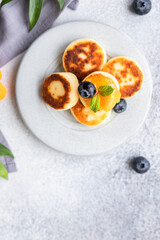 Cottage cheese pancakes, sweet curd fritters with blueberry and physalis, concrete background. Syrniki with jam and berries for a healthy breakfast.