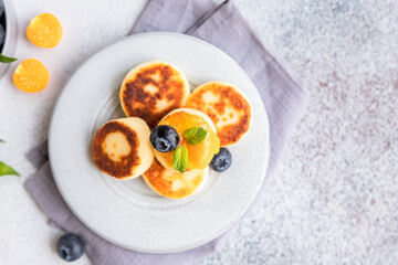 Cottage cheese pancakes, sweet curd fritters with blueberry and physalis, concrete background. Syrniki with jam and berries for a healthy breakfast.