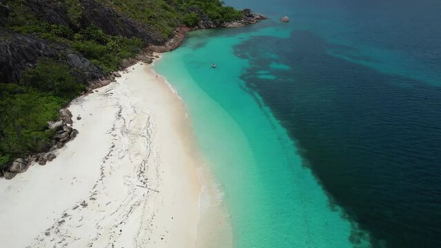 Aerial View of Curieuse Island Seychelles beach with rocky coastline and boat anchored in turquoise clear water