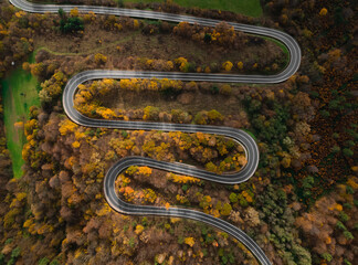 Autumn winding road in a mountain surounded by an autumn forest in Europe.