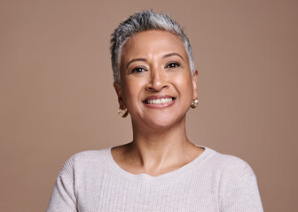 Face, beauty and portrait of a senior woman with a smile standing with natural makeup in studio. Wellness, cosmetics and happy elderly lady with healthy skin posing while isolated by brown background