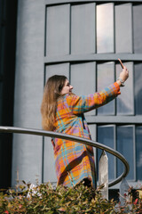 Smily woman dressed in vivid colours taking a selfie in modern city. Vertical shot. High quality photo