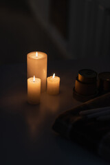 candles burning near canned food and warm blanket during energy blackout.