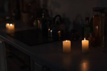 kitchen counter with kitchenware and lit candles during energy blackout.
