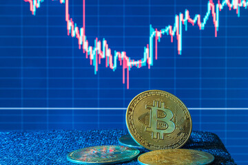Close-up of bitcoin coin against a screen with a rising cryptocurrency value graph. Investors hope for BTC to rise soon. Financial crisis.