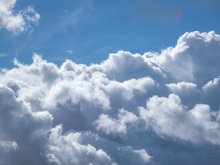 View of sky with fluffy white clouds in a sunny day. Background of dark sky sunlit with beautiful white clouds