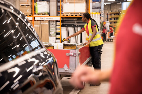 Side view of female sales staff scanning supplies through bar code reader at checkout counter