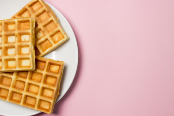 Homemade waffles on a pink background. Tasty breakfast