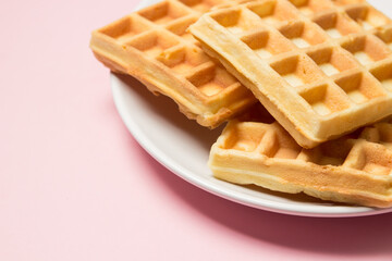 Homemade waffles on a pink background. Tasty breakfast