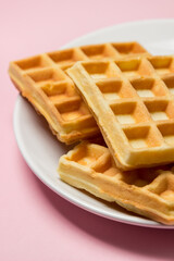 Homemade waffles on a pink background. Tasty breakfast