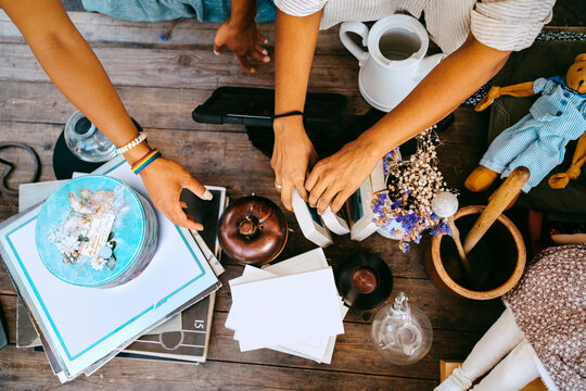 Directly above view of female partners arranging various merchandise on table at flea market