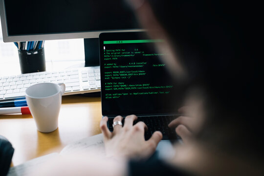 Cropped image of computer programmer coding over laptop while working in office