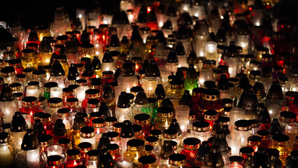 Lot of burning candles at night in cemetery.Glass inextinguishable lamps for cemetery.Day of remembrance and mourning for the dead.All Saints' Day.Commemorative candles as decor.Cemetery lamps.