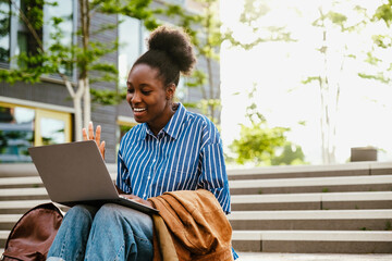 Young beautiful smiling african woman holding video conference with laptop