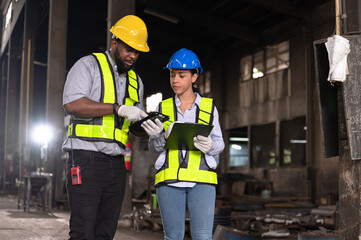 Latin America woman engineer working with engineer African American finger point to tablet computer at factory