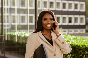 Young black businesswoman talking on cellphone while walking outdoors